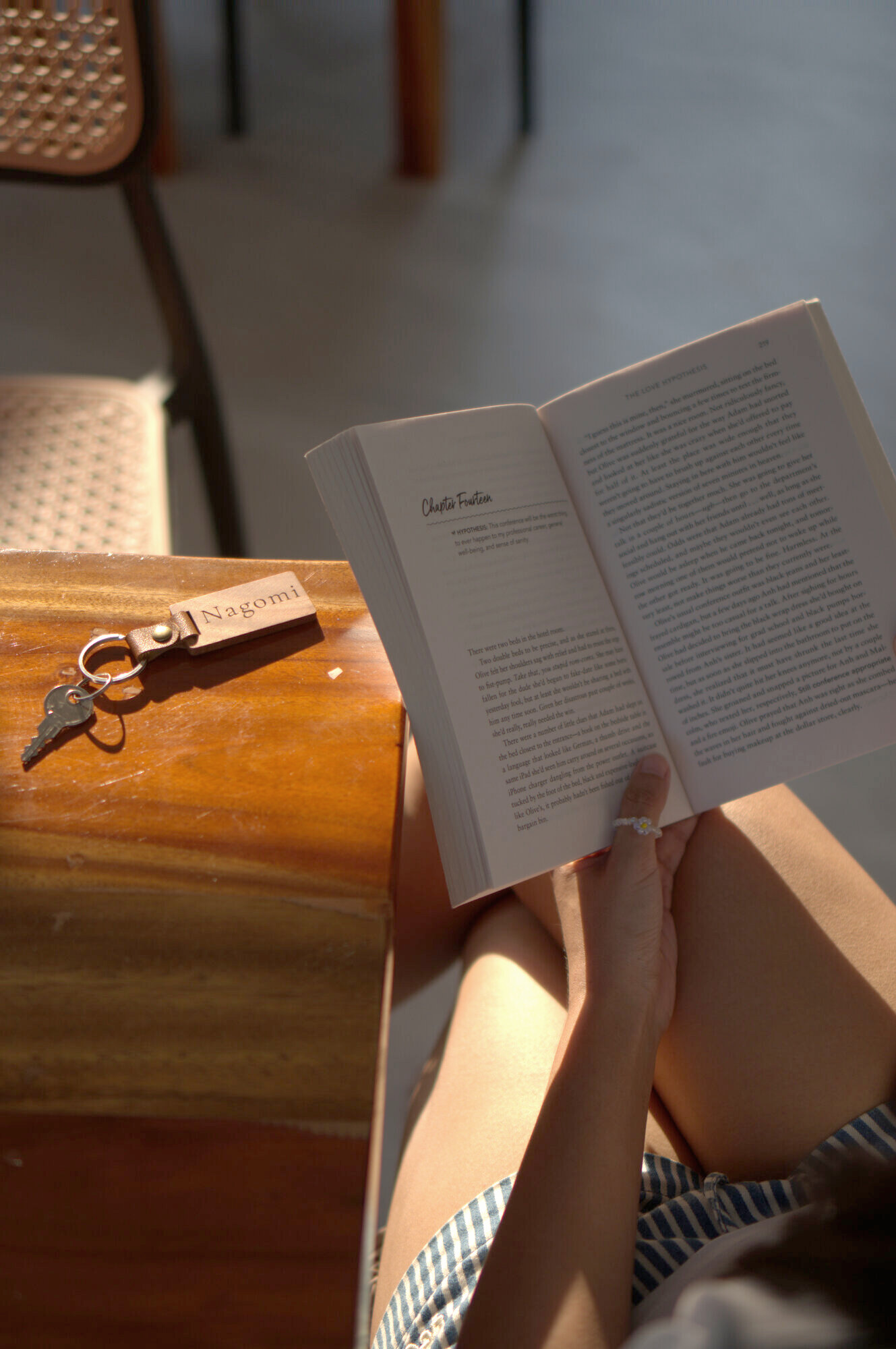 A Nagomi villa key beside a book in warm afternoon light